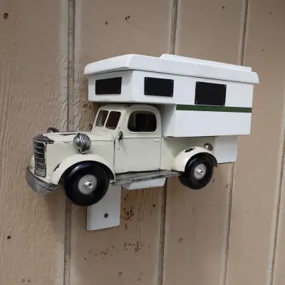 A 1930's era looking tin truck customized with a newly built camper birdhouse structure mounted in t...