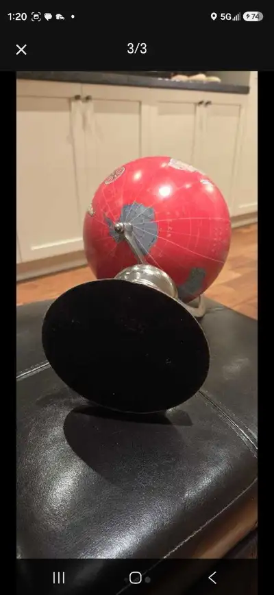 This decorative world globe features a striking red design with a polished metallic stand, making it...