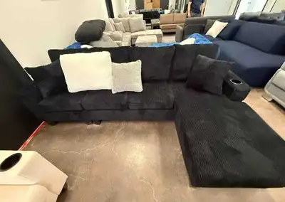 This black corduroy sectional sofa is in good condition, featuring a convenient integrated cup holde...