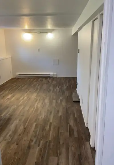 This bright and well-maintained basement suite features a functional kitchen area with a stove, sink...