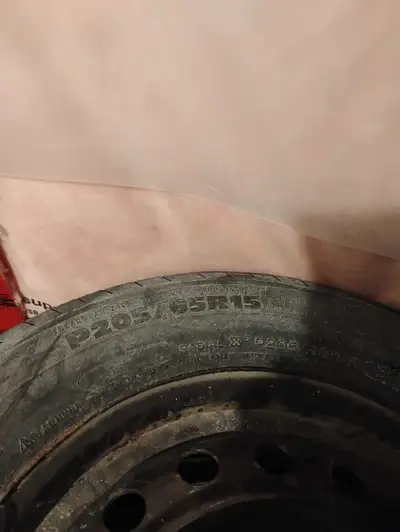 Offering a P205/65R15 Michelin all-season tire mounted on a steel rim, perfect as a spare or for rep...