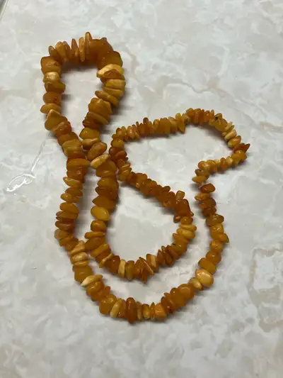 This is a used amber necklace featuring irregularly shaped amber pieces, strung together to create a...