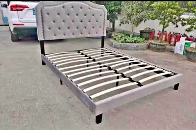 This queen-size bed frame features a stylish grey upholstered headboard with button detailing and a...