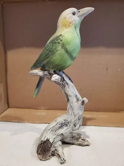 A resin figure/statuette of a green bird sitting on a branch. It's about 9" tall, so fairly large fo...