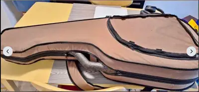 Durable TRIC Classical guitar case has tan fabric exterior with black trim. Lightweight expanded pol...