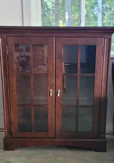 Two matching glass paned cherry solid wood display cabinets with lighting, heavy glass shelving. One...