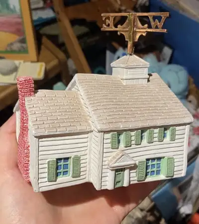 White house with green shutters and a brick chimney. Features a spinning weathervane on the roof tha...