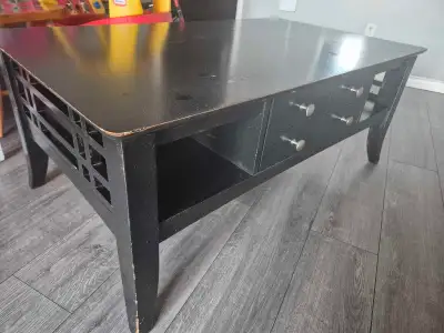 Selling a solid black wooden coffee table in great functional condition with some light wear and tea...