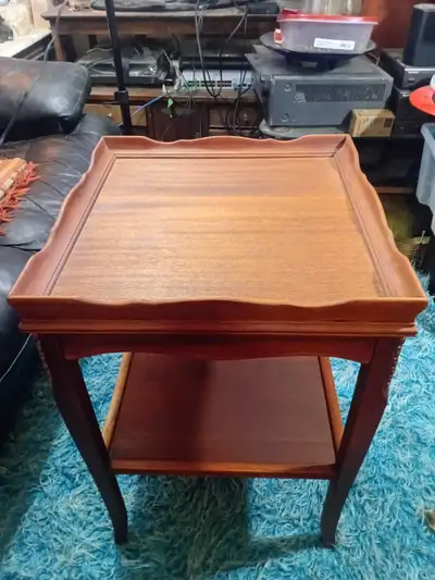 This is a used side table that has a classic design and includes a lower shelf for additional storag...