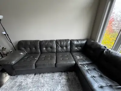 This large, grey faux leather sectional sofa with light grey cushions is perfect for a big living ro...