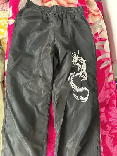 Cool black track pants. Has white embroidered dragon design on one leg. Elastic waistband and cuffed...