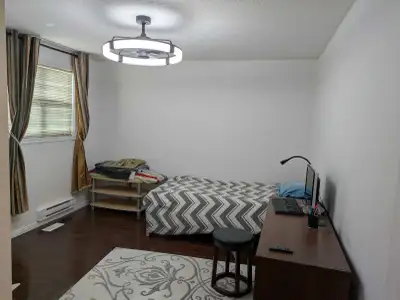 This clean and well-lit private room features hardwood flooring, a comfortable bed, and a functional...