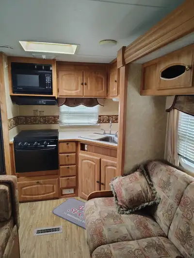 spacieuse roulotte de voyage présente un intérieur lambrissé de bois avec une cuisine complète compr...