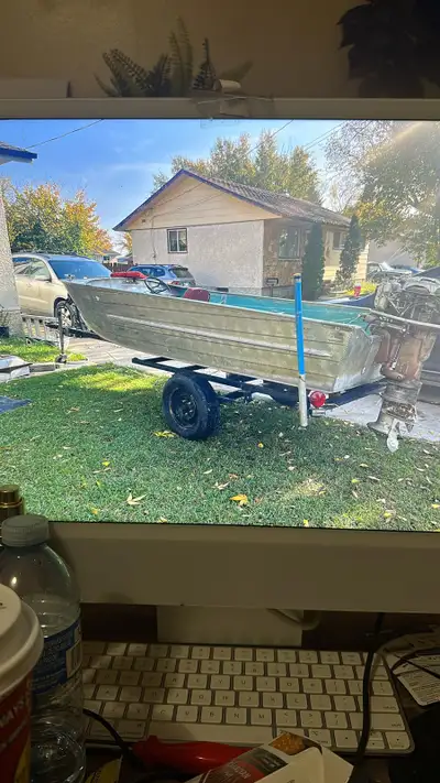 This is an older aluminum boat sitting on a trailer, perfect for someone looking for a project or a...