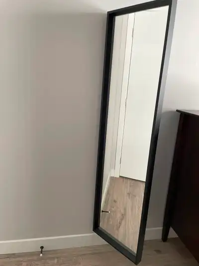 Like new black framed wall mirror. The mirror can be angled if you choose to mount it with the hinge...