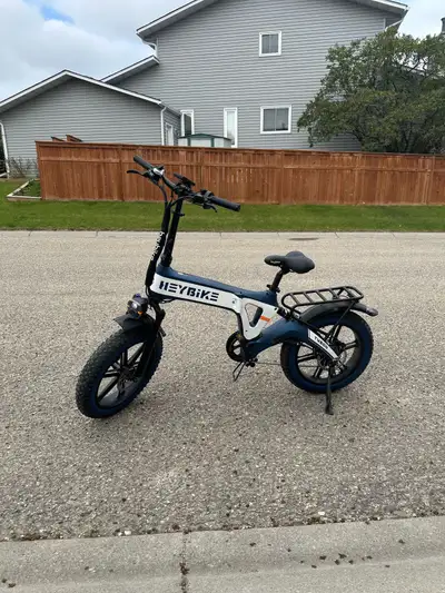 Folding electric bike. Features fat tires, rear rack, integrated headlight and taillight. Includes c...