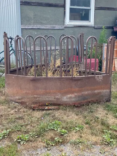 This used metal hay feeder is designed for efficient feeding of livestock, particularly cattle or ho...