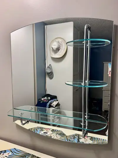 This mirror makes a lovely compliment to a bathroom or bedroom. It has three small shelves on the ri...