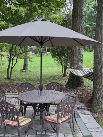 Fairly New 6 seater cast aluminium patio set with round table and umbrella. Complimentary NEW cushio...