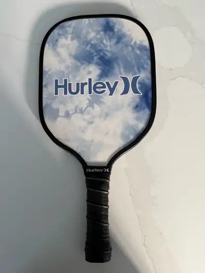 Brand new Hurley pickleball paddle with a blue tie-dye design. It's got a black grip for comfort. A...