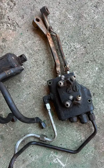 Hydraulic valves with control levers and lift cylinder off an early John Deere 316 with two hydrauli...