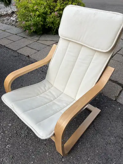This IKEA Poäng armchair features a durable bentwood frame in a light birch finish paired with a com...