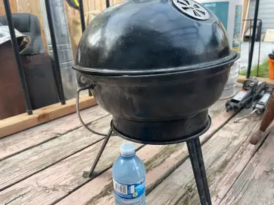 Small, portable charcoal grill. Black metal construction. Features a hinged lid with vent. Used cond...