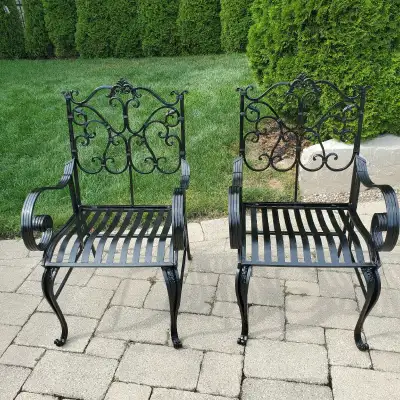 2 beautiful ornate wrought iron chairs .