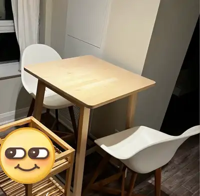 This Ikea bar table and chairs set features a light wood table and two white chairs, perfect for a m...