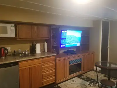 Basement room with cable TV, internet . Has small sink, bar fridge and microwave. cabinets with elec...