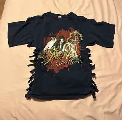 Black T-shirt with a graphic of the Jonas Brothers on the front and a list of the 2008 tour dates on...