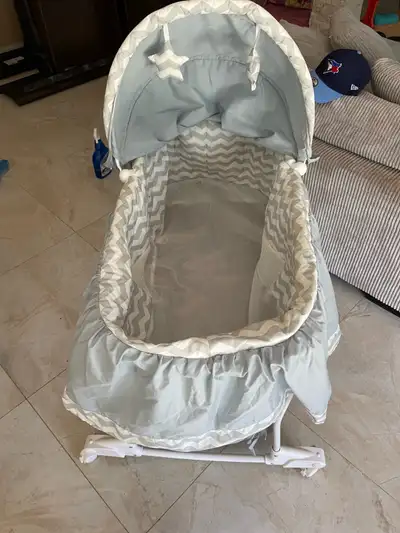 This is a used baby bassinet in good condition, perfect for newborns. It features a hood to shield y...