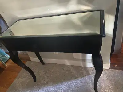 This black console table features a mirrored top, adding a touch of sophistication to any room. This...