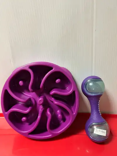 Pets Two Pieces purple Outward Hound Fun Feeder and a purple Kong dumbbell-shaped treat dispenser, b...