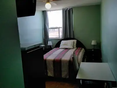 A furnished room complete with a double bed, two bedside tables, two dressers and small desk with a...