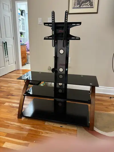 This is a sleek, used TV stand with a built-in TV mount and black glass shelves, perfect for a moder...