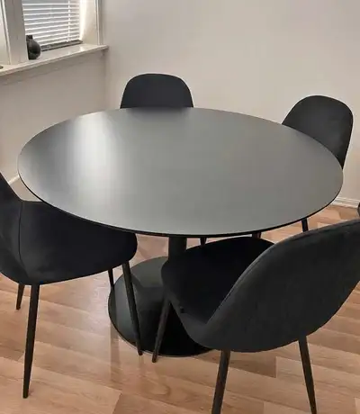This round dining table is perfect for smaller spaces, offering a modern look with its sleek, black...