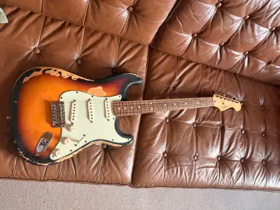 Cette guitare électrique Fender Stratocaster offre une esthétique vintage avec sa finition sunburst...