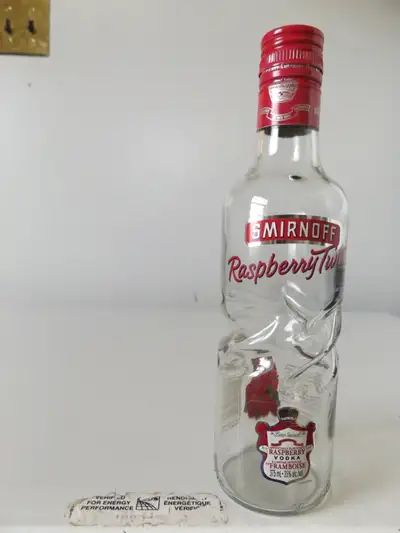 This is an original vintage empty glass Smirnoff Raspberry Twist mini bottle. The bottle measures 9"...