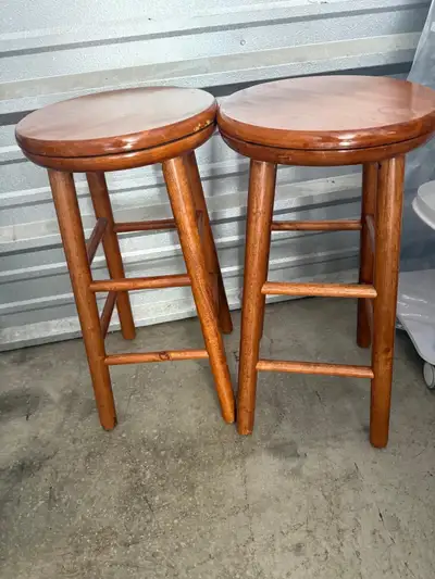 These are a pair of round, wooden bar stools, perfect for adding a rustic touch to your kitchen or b...