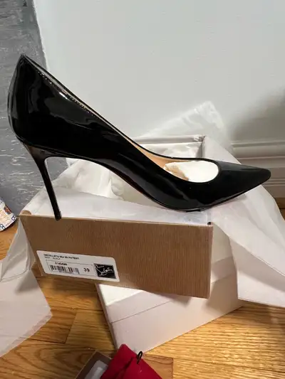 Elevate your style with these stunning Christian Louboutin black patent leather heels, size 39. Thes...