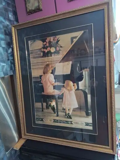Large framed art print featuring two young girls at a Steinway & Sons piano. Gold coloured frame. Be...