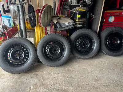 These pre-owned Bridgestone Blizzak DM-V2 winter tires mounted on black steel rims provide exception...