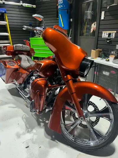 This stunning custom Harley-Davidson touring motorcycle features a vibrant metallic orange paint job...