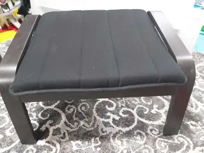 This is a used IKEA footrest with a black cushion and a dark brown wooden frame, perfect for relaxin...
