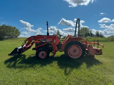 Acreage tractor with aftermarket loader and tiller.