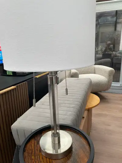 This elegant table lamp features a modern design with a clear glass central column and a brushed nic...