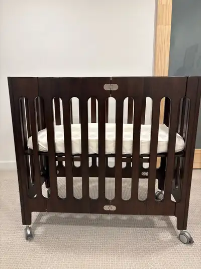 GUC mini crib with organic mattress. Foldable and easily moves around on wheels.