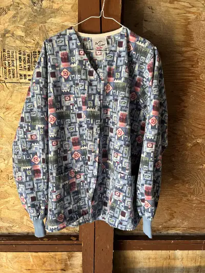 This is a stylish Dr. Mac scrub jacket in a size large, featuring a unique geometric pattern in blue...