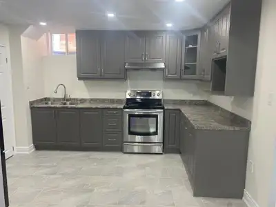 This newly renovated and clean basement apartment features a modern kitchen with grey cabinetry, sta...